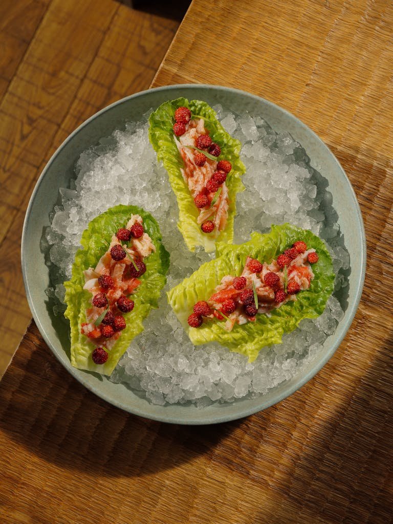 Gourmet lettuce wraps topped with fresh salmon and berries, served on crushed ice.