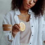 Close-up of a woman squeezing lemon into a glass for a refreshing drink.