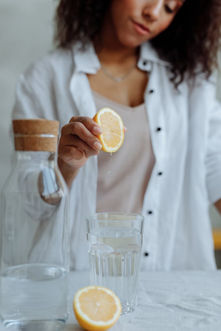 Close-up of a woman squeezing lemon into a glass for a refreshing drink.